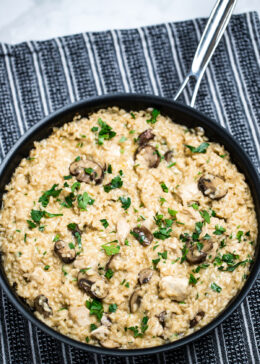 A skillet full of gluten free mushroom chicken risotto on a table.