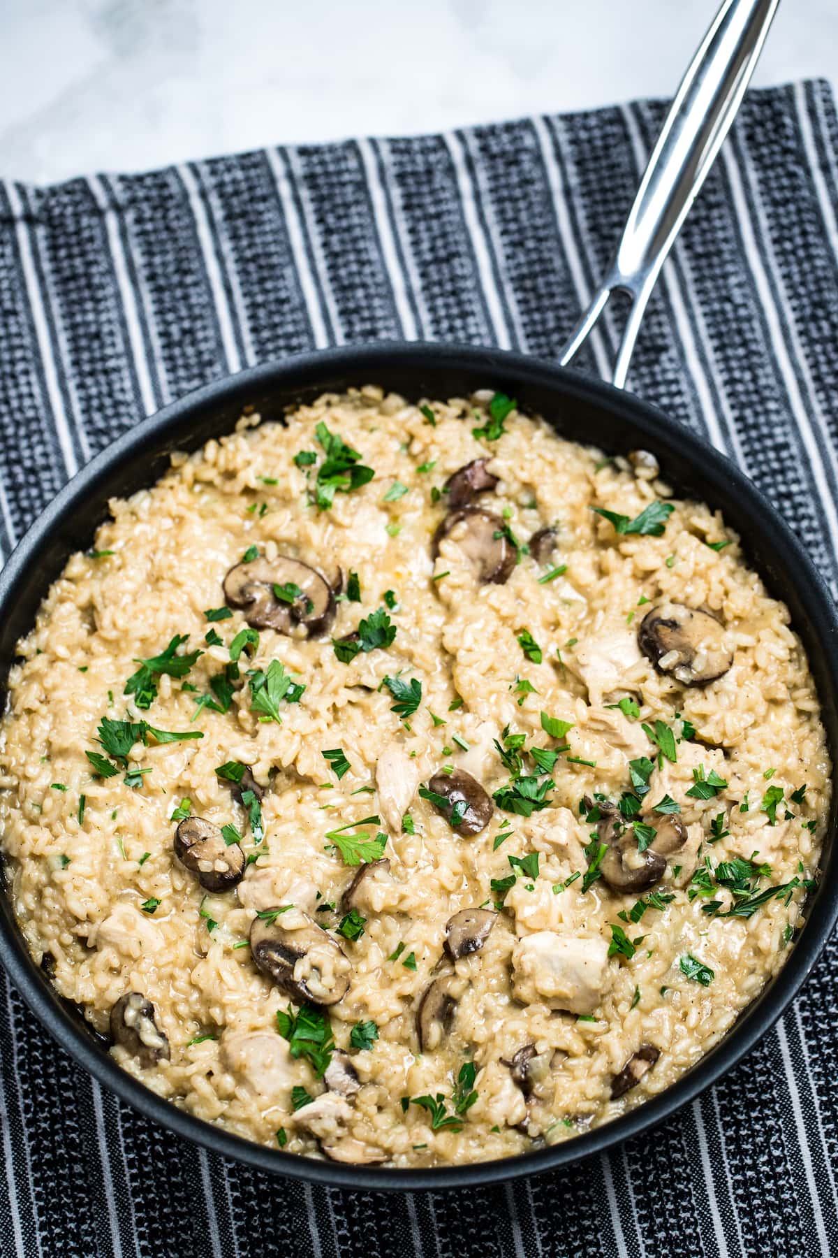 A skillet full of gluten free mushroom chicken risotto on a table.