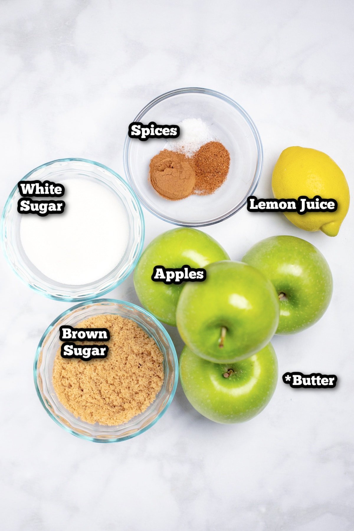 Individual ingredients for cinnamon baked apples on a marble table.