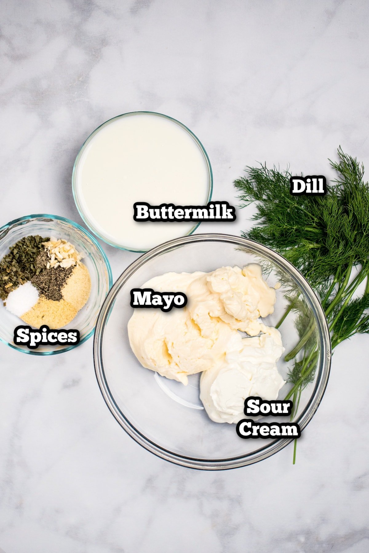 Ingredients for buttermilk ranch dressing on a marble table.