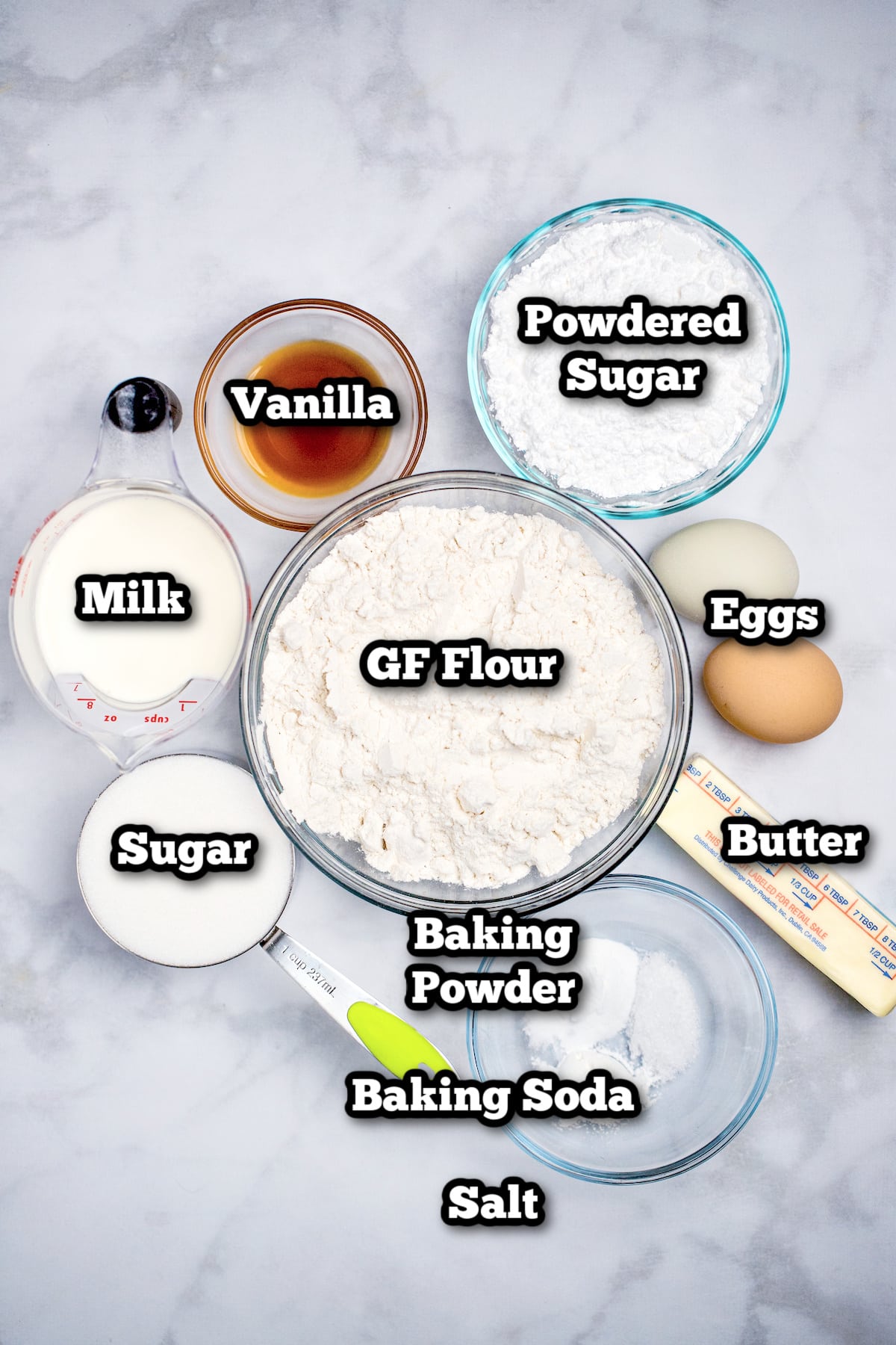 Individual ingredients for powdered sugar donuts on a table.