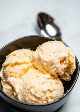 A bowl full of three scoops of no churn ice cream next to a spoon.