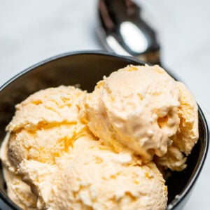 A bowl full of three scoops of no churn ice cream next to a spoon.