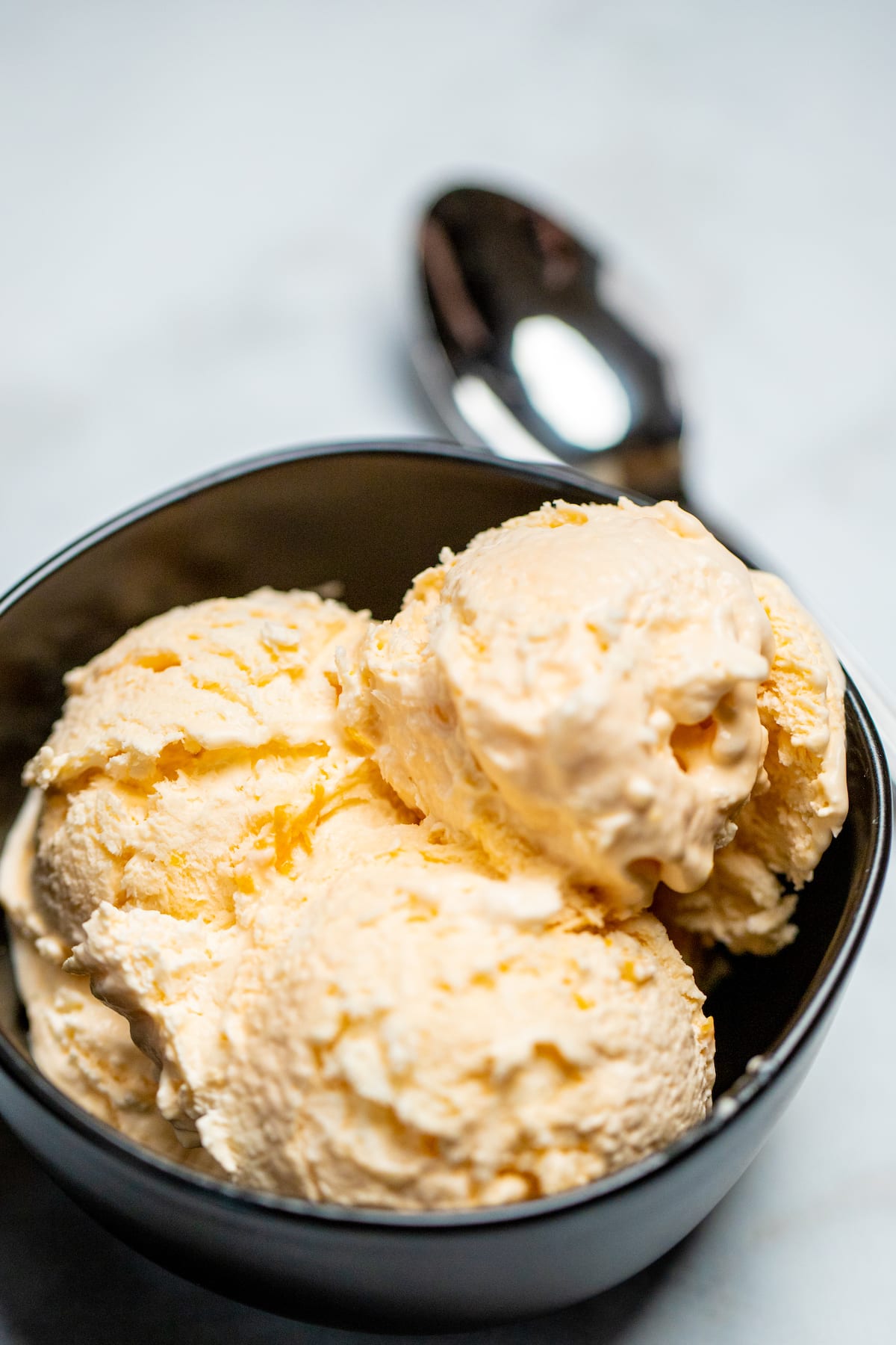 A bowl full of three scoops of no churn ice cream next to a spoon.