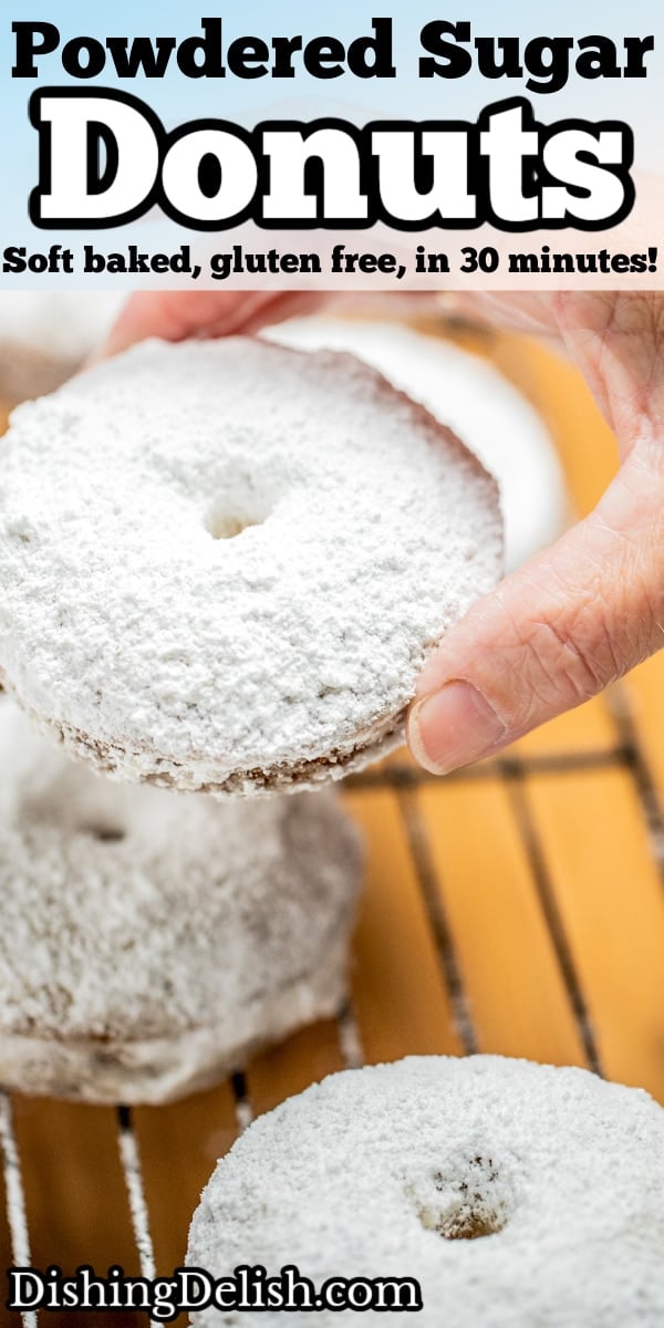 Pinterest pin with a hand holding a powdered sugar donut over a cooling rack.