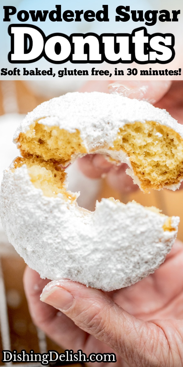 Pinterest pin with a hand breaking a powdered sugar donut in half.