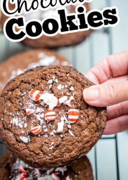 Pinterest pin of a hand holding a peppermint chocolate cookie above other cookings cooling on a rack.