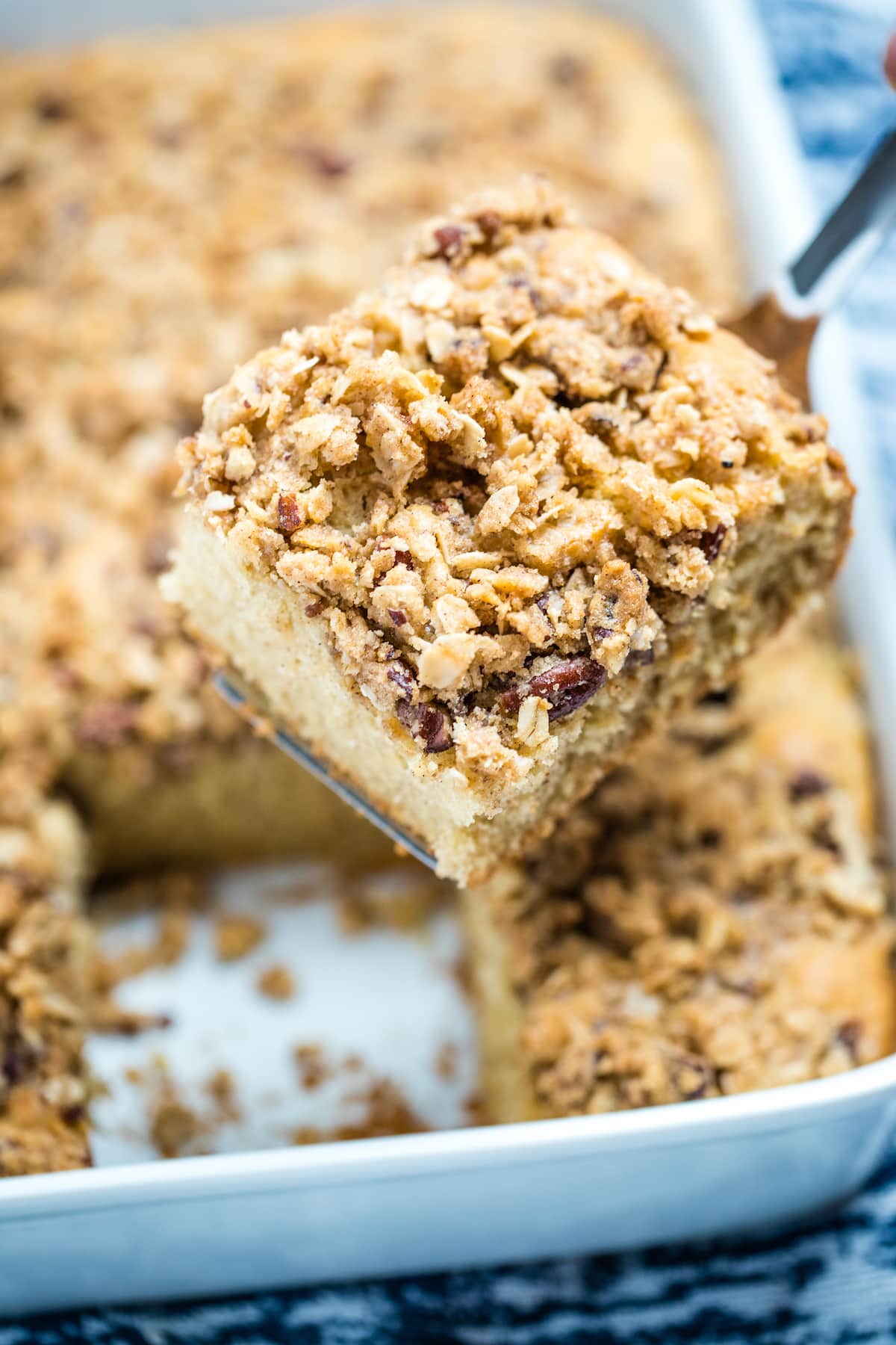 A spatula holding a piece of gluten free coffee cake above the baking dish.