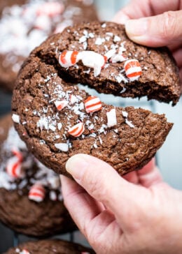 Two hands breaking a peppermint chocolate cookie in half.