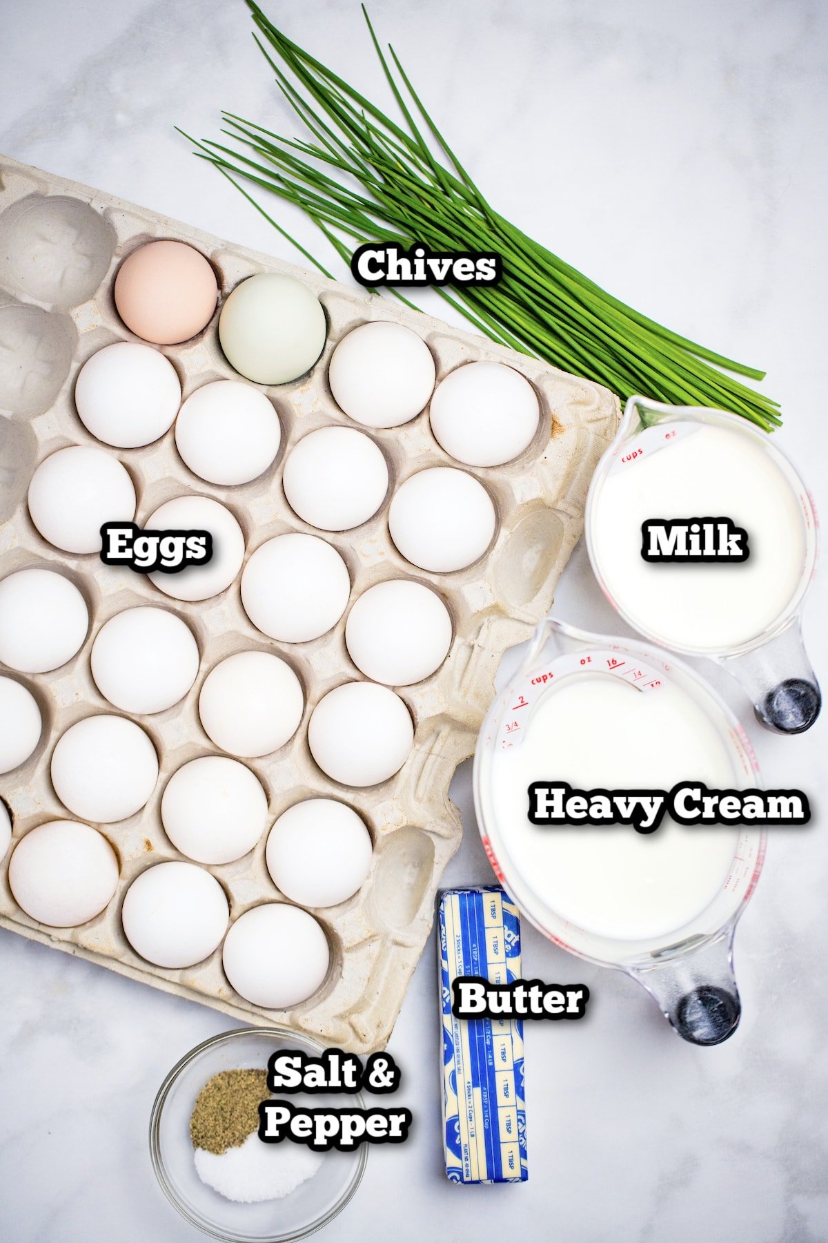 Individual ingredients for baked scrambled eggs on a marble table.