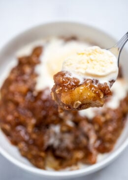 Pinterest pin with a bowl of apple crisp and a spoonful topped with vanilla ice cream.