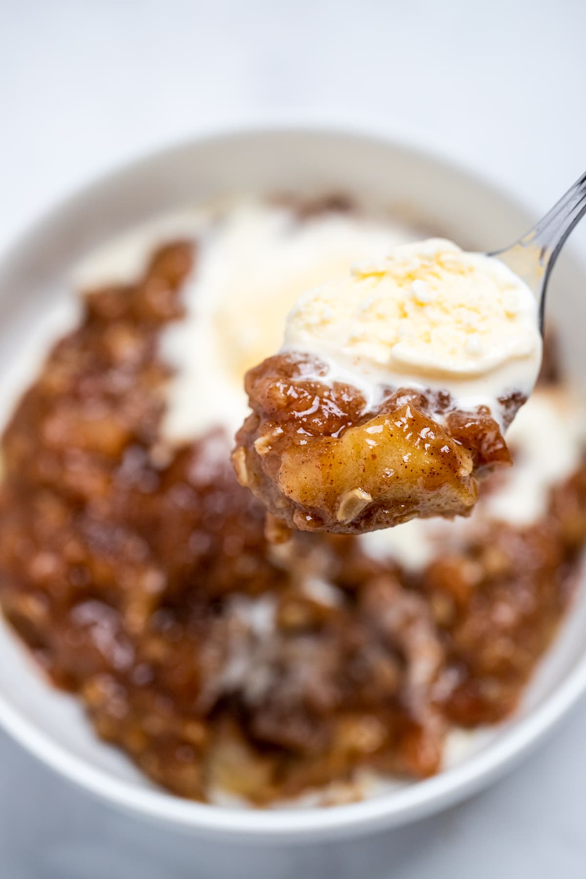 Pinterest pin with a bowl of apple crisp and a spoonful topped with vanilla ice cream.