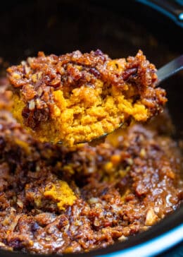 A spoon lifting a portion of crockpot sweet potato casserole out of the slow cooker.