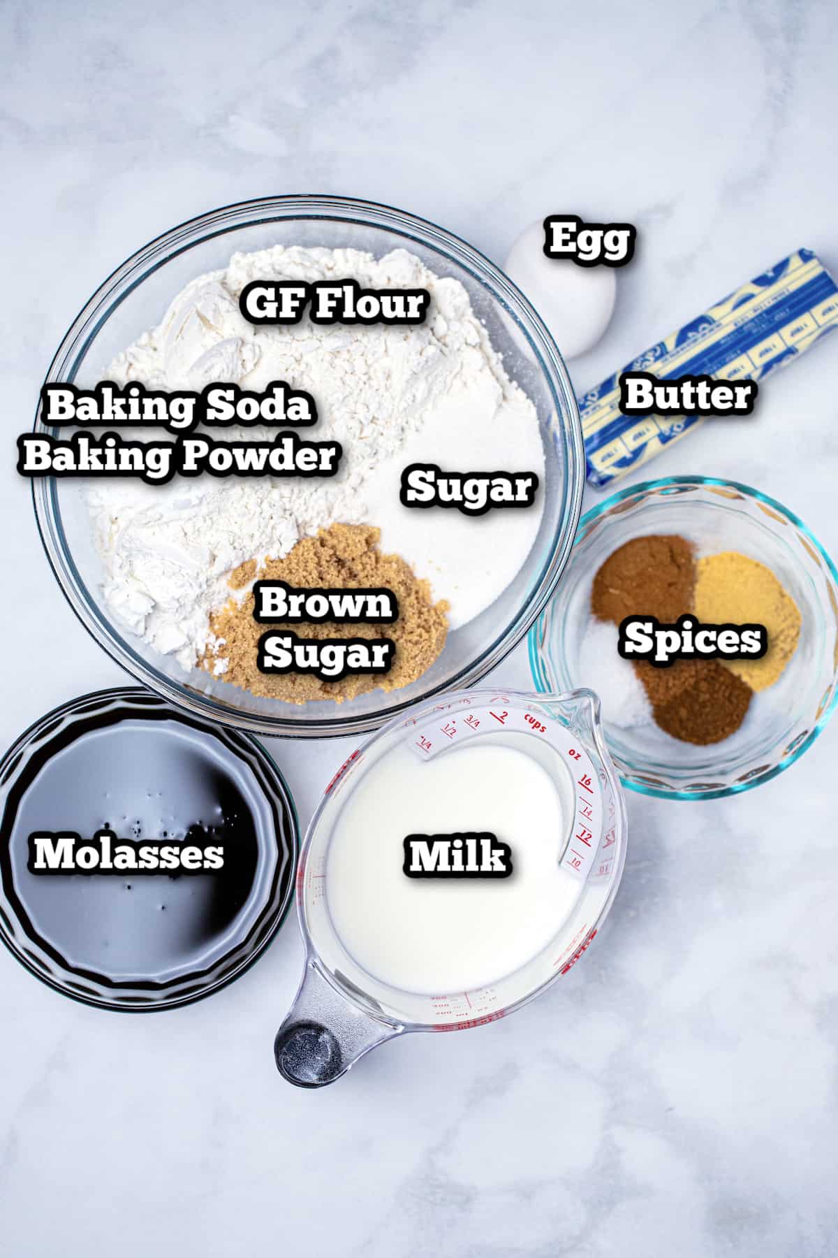 Individual ingredients for gingerbread cupcakes on a marble table.
