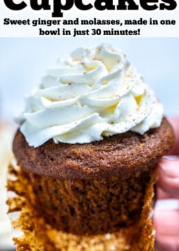 Pinterest pin with a hand holding a gingerbread cupcake topped with frosting above a wooden cutting board and other cupcakes.