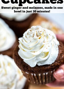 Pinterest pin with a hand holding a gingerbread cupcake topped with frosting above a wooden cutting board and other cupcakes.