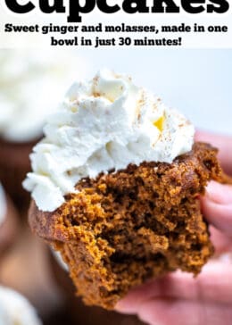 Pinterest pin with a hand holding a gingerbread cupcake topped with frosting with a bite taken out of it, above a wooden cutting board and other cupcakes.