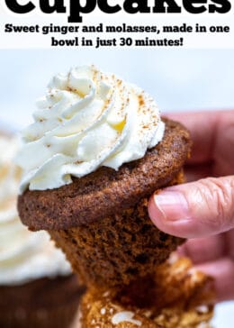 Pinterest pin with a hand holding a gingerbread cupcake topped with frosting above a wooden cutting board and other cupcakes.