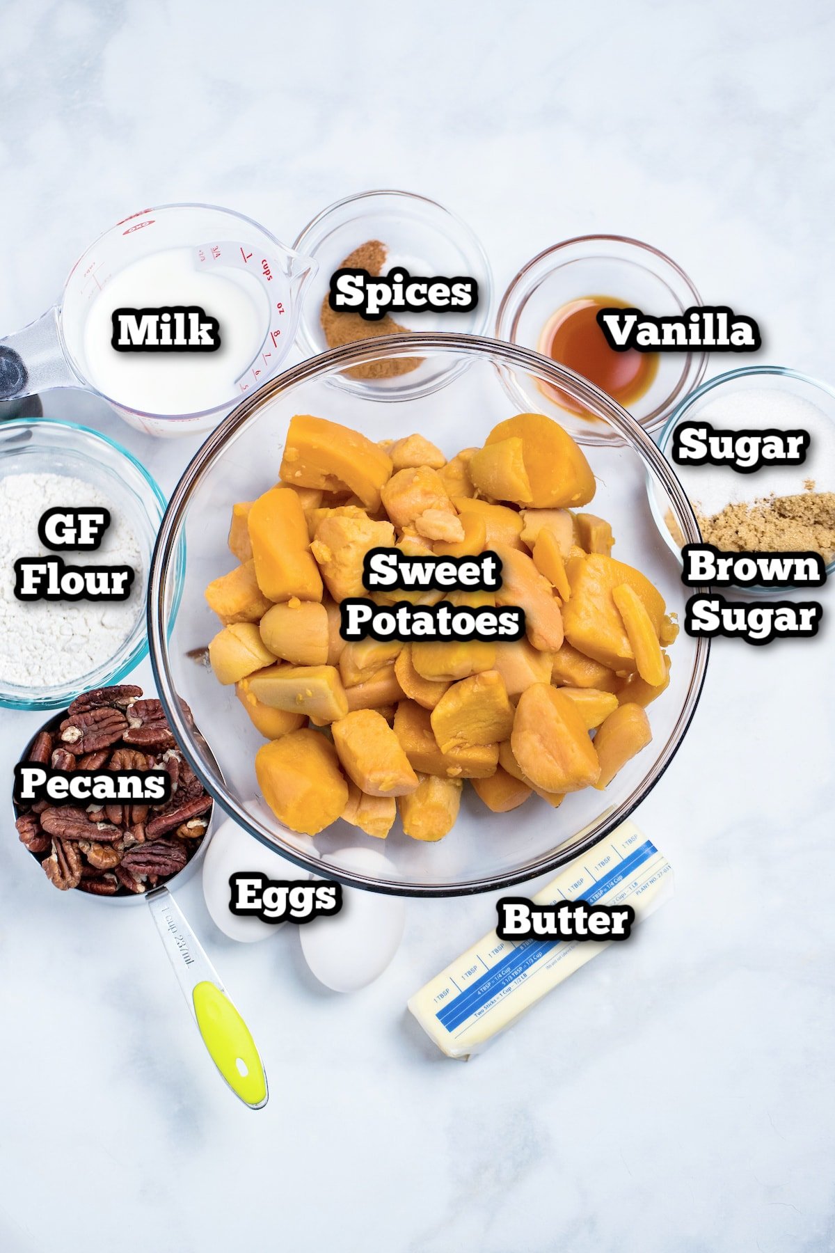 Individual ingredients for crockpot sweet potato casserole on a marble table.
