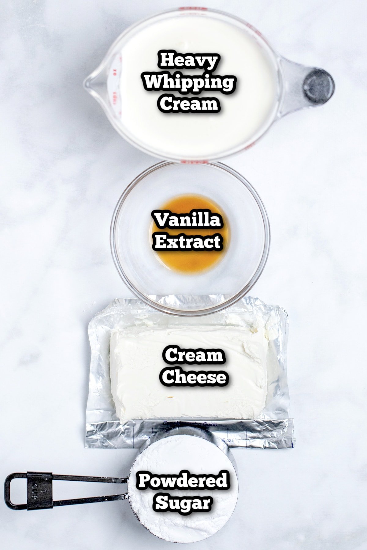 Individual ingredients for whipped cream cheese frosting on a marble table.