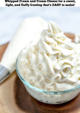 Pinterest pin of whipped cream cheese frosting piped into a glass bowl next to a piping bag on a wooden cutting board.