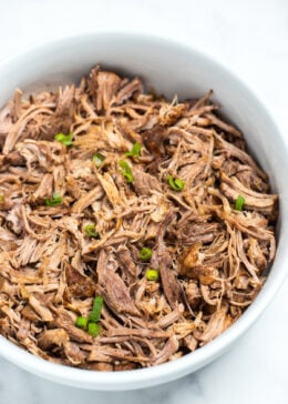 Shredded instant pot pork shoulder in a bowl on a table.