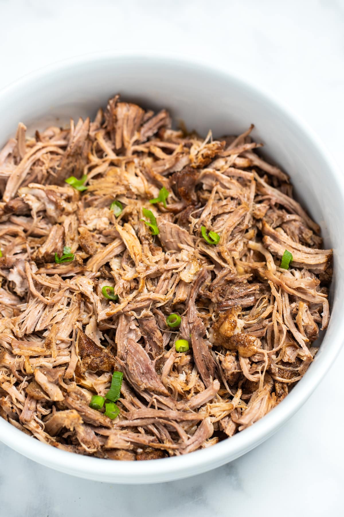 Shredded instant pot pork shoulder in a bowl on a table.