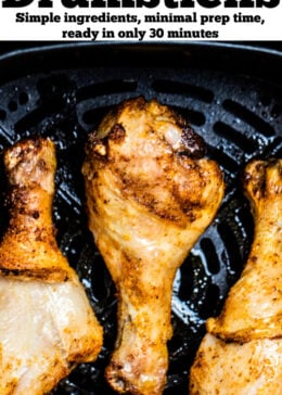 Pinterest pin with three chicken drumsticks in an air fryer.