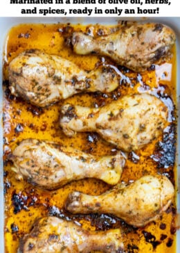 Pinterest pin with a baking dish with cooked chicken drumsticks covered in marinade.