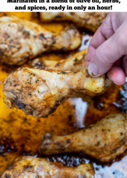 Pinterest pin with a baking dish with cooked chicken drumsticks covered in marinade and a hand taking a drumstick.