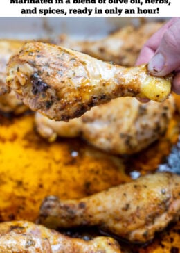 Pinterest pin with a baking dish with cooked chicken drumsticks covered in marinade with a hand taking a drumstick.