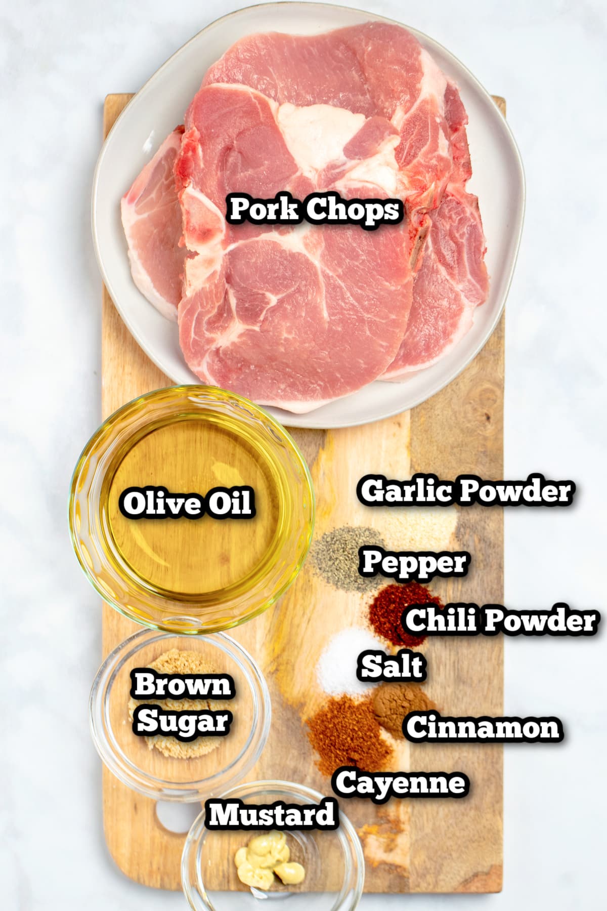 Individual ingredients for marinated pork chops on a wooden cutting board.