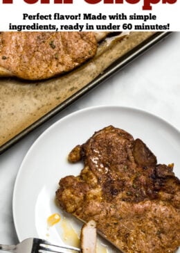 A marinated pork chop on a plate with a fork holding a slice of chop, next to a sheet pan with other cooked pork chops.