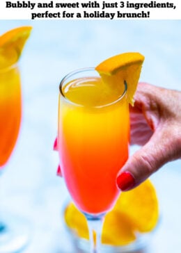 Pinterest pin with a hand holding a prosecco mimosa in front of a small bowl of orange slices.