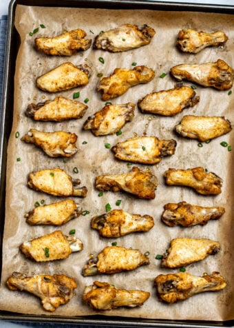 Instant pot chicken wings on a sheet pan lined with parchment paper topped with green onions.