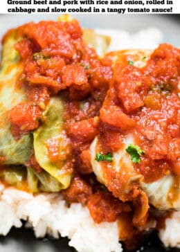 Pinterest pin with two cabbage rolls topped with tomato sauce on top of rice on a plate.