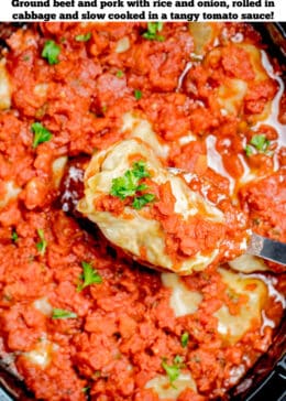 Pinterest pin with a spoon lifting a cabbage roll out of the slow cooker topped with tomato sauce and fresh parsley.