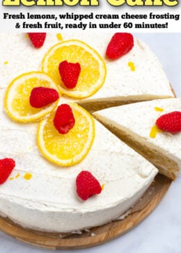 Pinterest pin with a lemon cake topped with lemon slices, sprinkles, and raspberries on a wooden cake stand with a slice being lifted out of it.