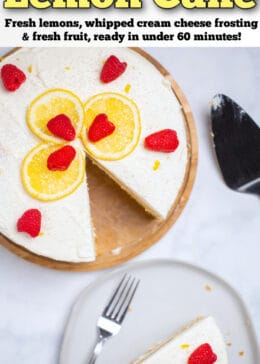 Pinterest pin with a lemon cake topped with lemon slices, sprinkles, and raspberries on a wooden cake stand, with a slice in front of the cake on a plate with a fork.