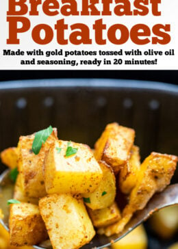 A spoon lifting air fryer breakfast potatoes out of an air fryer basket.