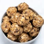 A bowl full of peanut butter oat balls on a table.