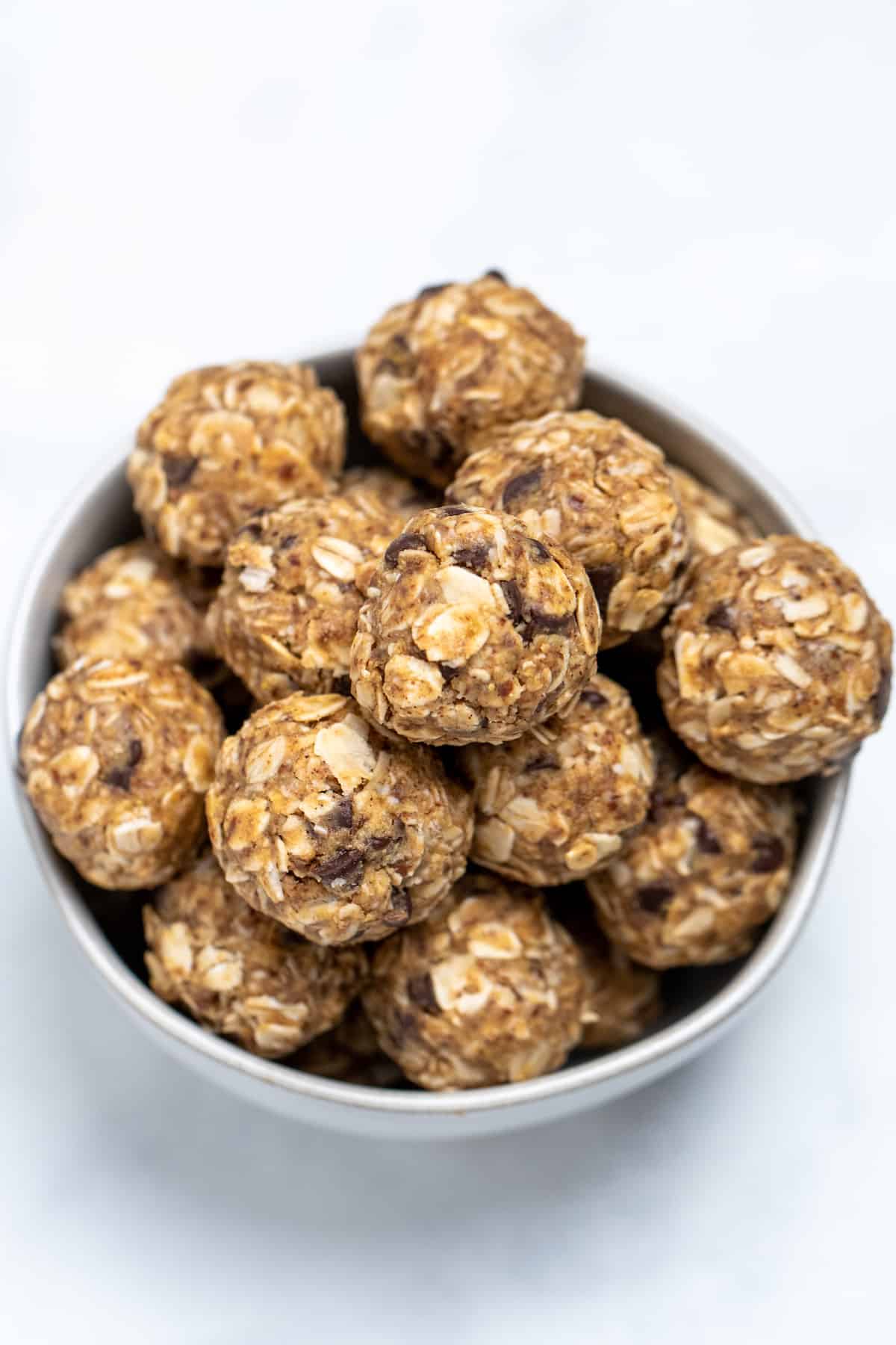A bowl full of peanut butter oat balls on a table.