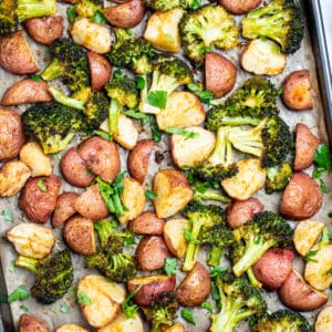 Roasted potatoes and broccoli on a sheet pan with parchment paper.