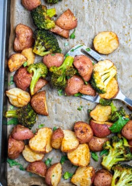 Roasted potatoes and broccoli on a sheet pan with parchment paper.