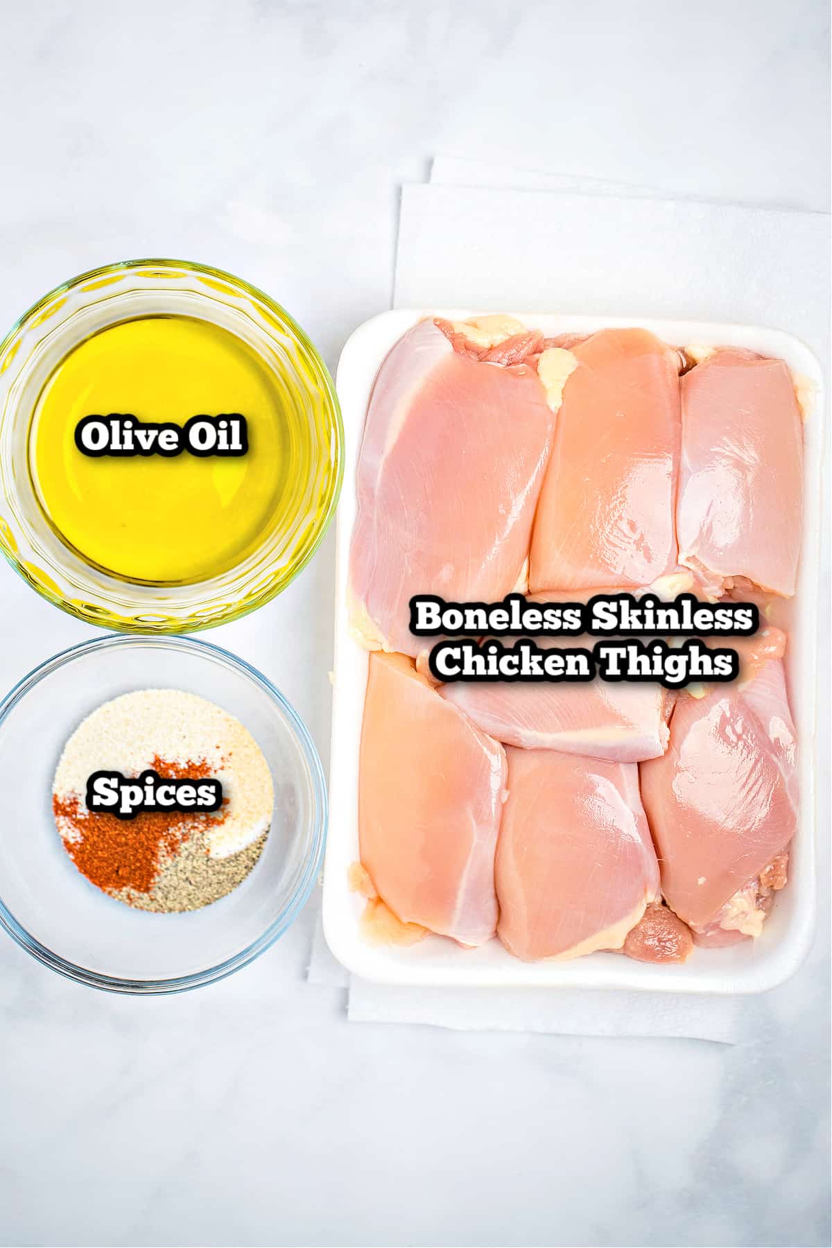 Individual ingredients for boneless skinless chicken thighs on a marble table.