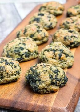 Spinach balls being served on a wooden cutting board.