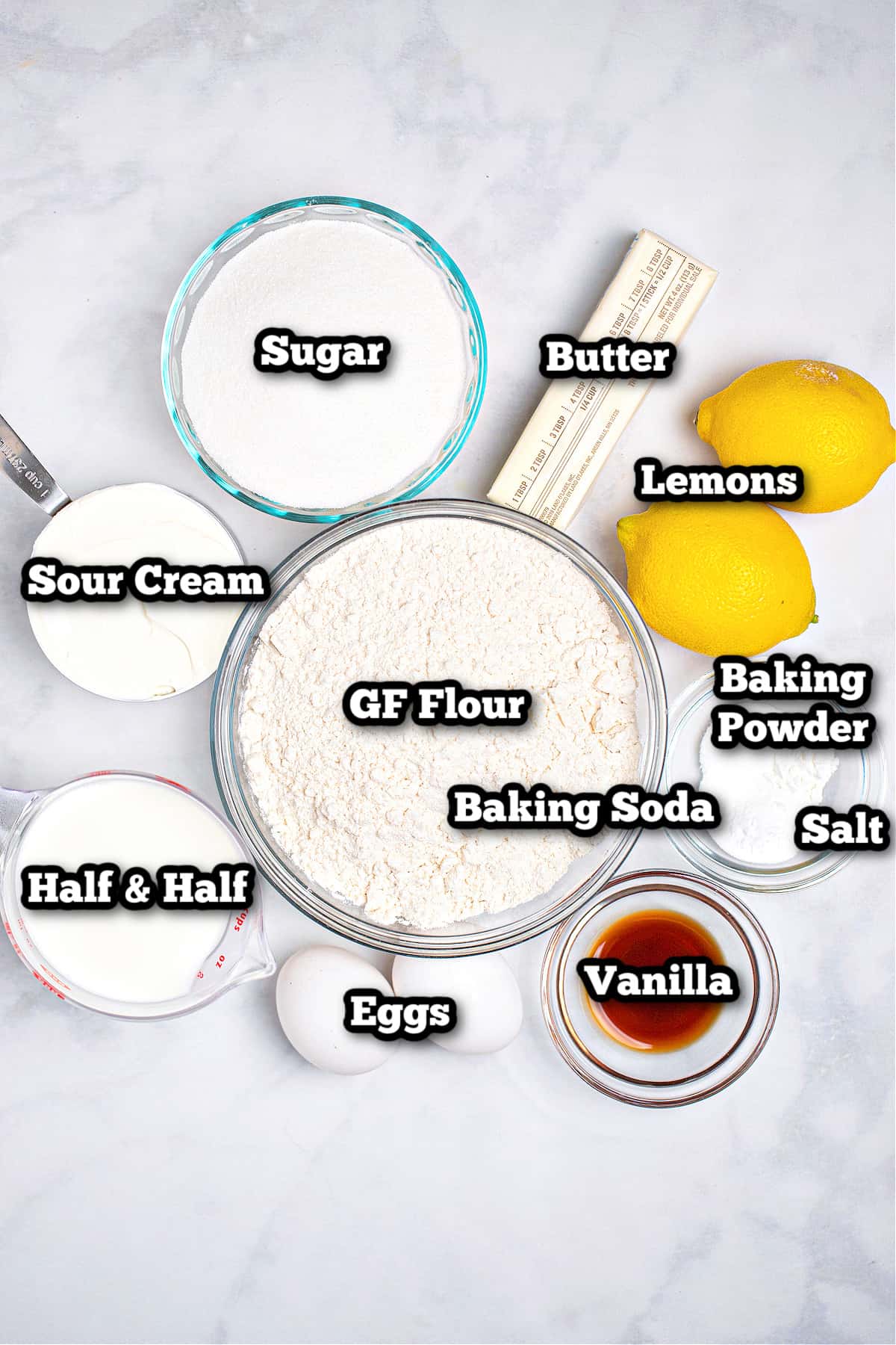 Individual ingredients for gluten free lemon cake on a marble table.