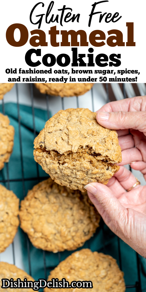 Pinterest pin with a hand breaking a cookie in half, over a cooling rack of other gluten free oatmeal cookies.