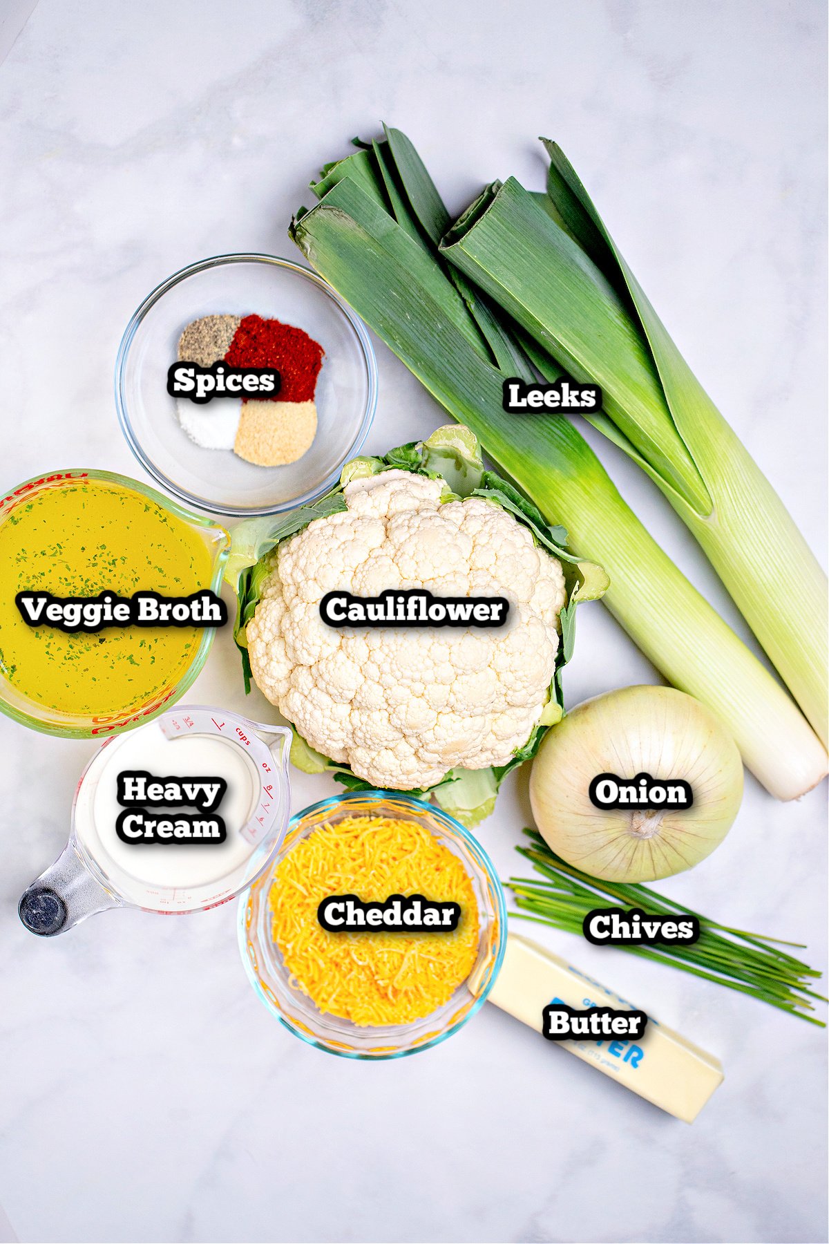 Individual ingredients for instant pot cauliflower soup on a marble table.