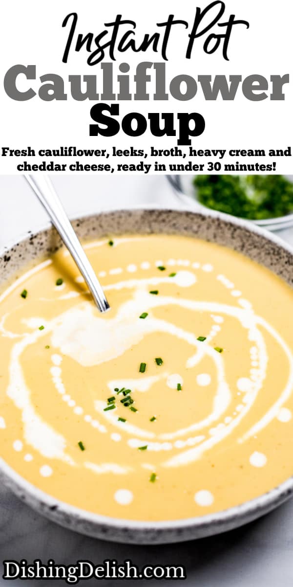 A bowl of cauliflower soup on a table, with cream drizzled on top and fresh chives.